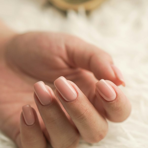 Hand with soft pink almond-shaped nails